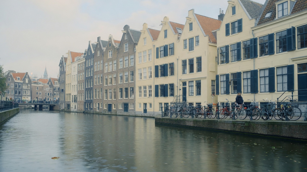 Amsterdam canal houses across calm water under soft overcast light